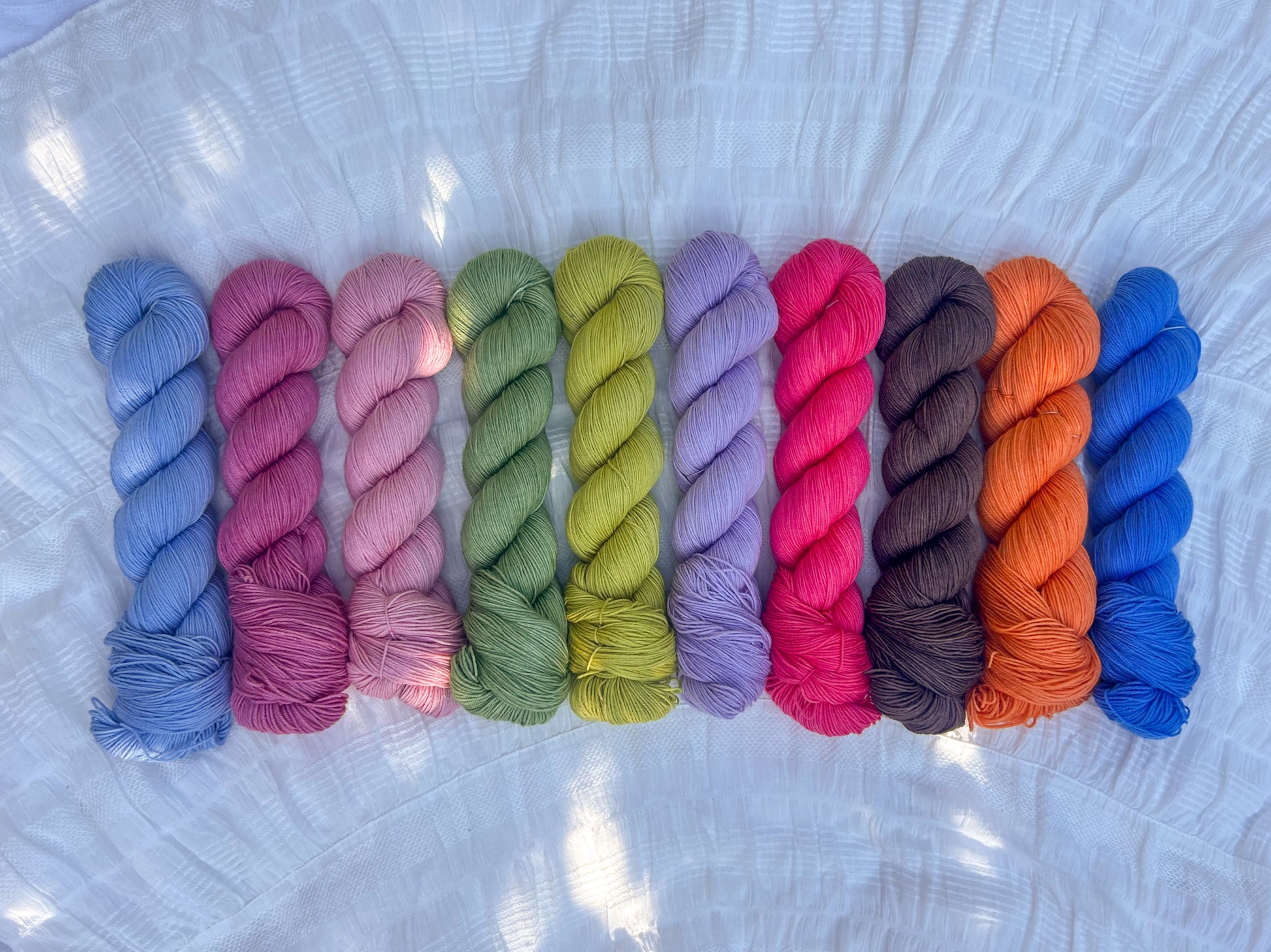 Row of colorful yarn skeins on a sock base on a textured white surface